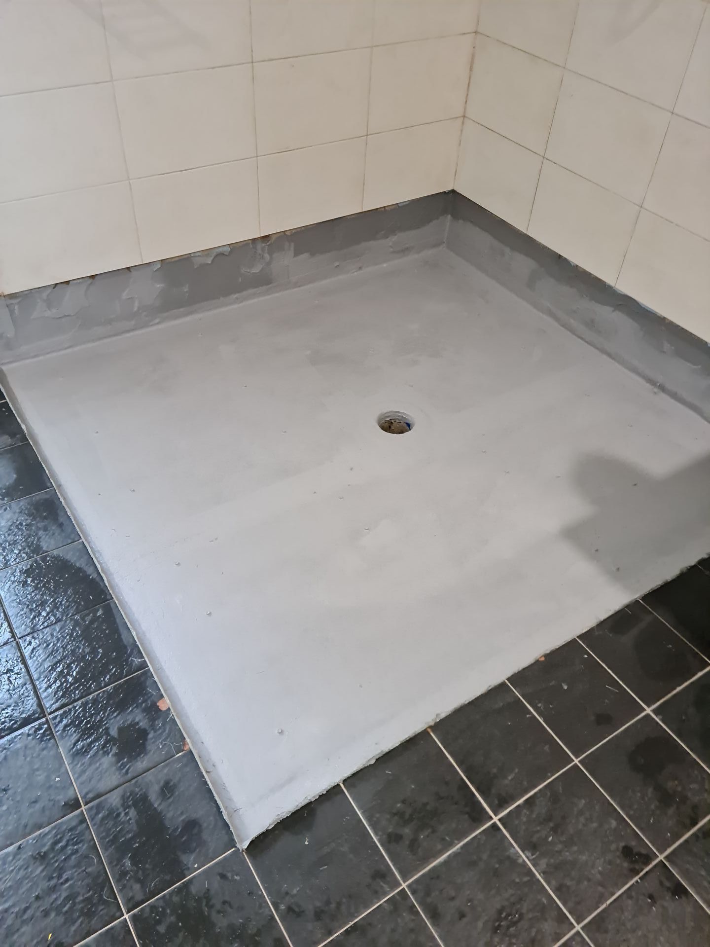 A shower stall in a bathroom with a hole in the floor — South Coast Flooring in Berkeley, NSW