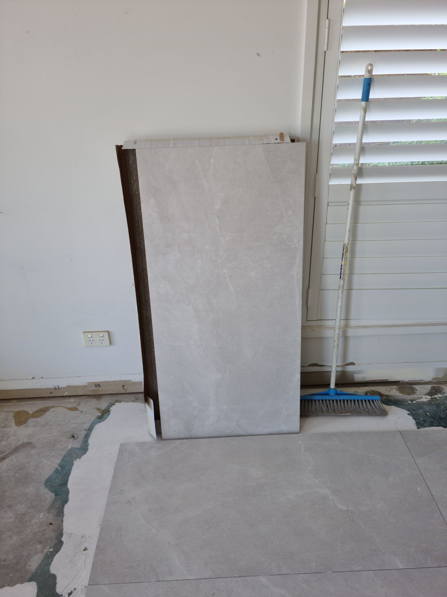 A piece of tile is sitting on the floor next to a broom — South Coast Flooring in Berkeley, NSW