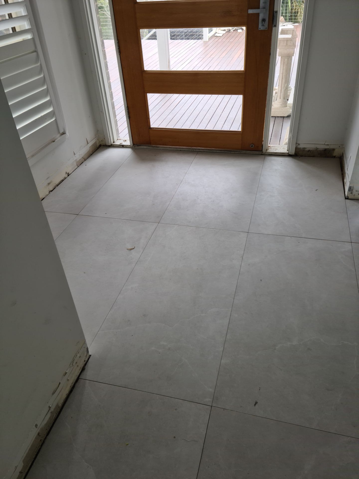 A hallway with a wooden door and a tiled floor — South Coast Flooring in Berkeley, NSW