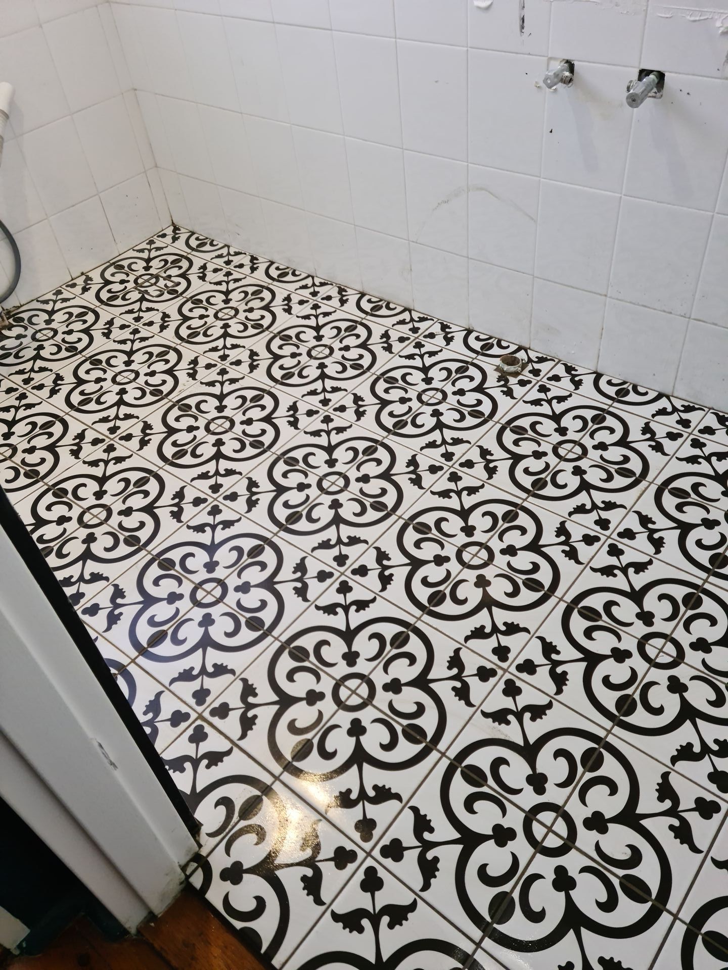 A black and white tile floor in a bathroom with a floral pattern — South Coast Flooring in Berkeley, NSW