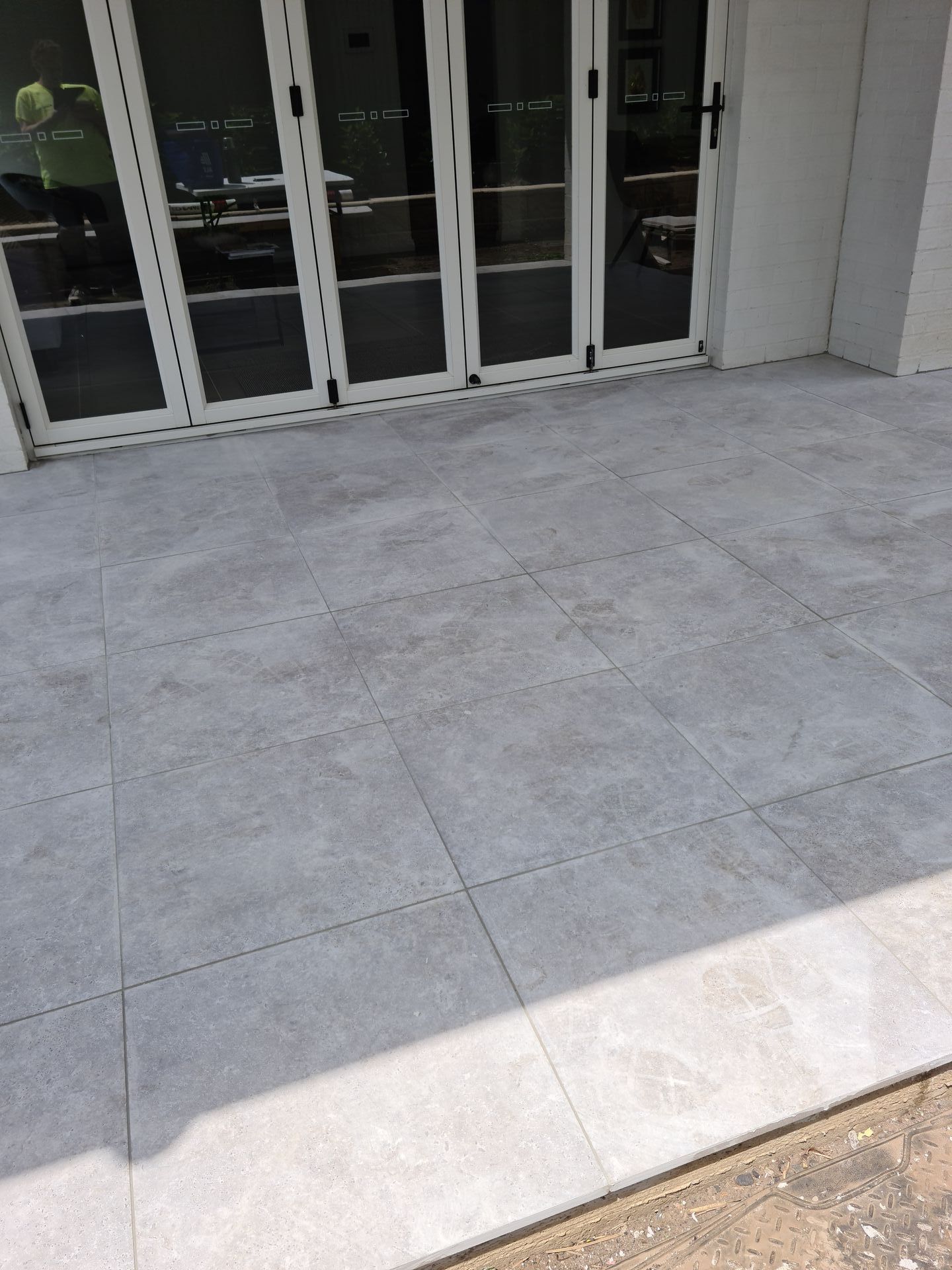 A patio with tiles and sliding glass doors in front of a building.