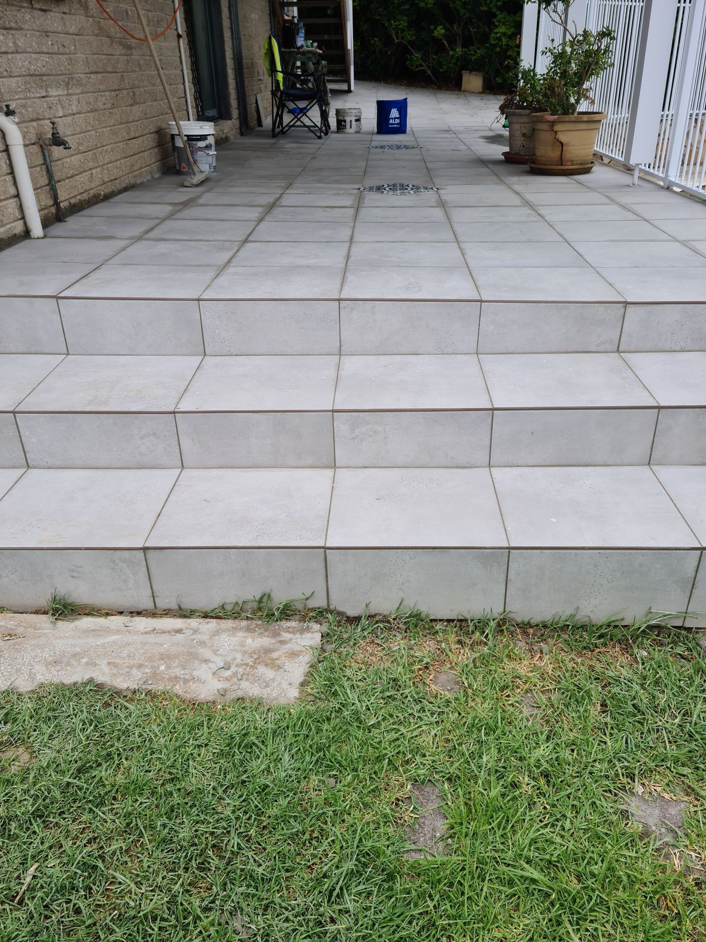 A patio with tiled steps and a potted plant in the grass — South Coast Flooring in Berkeley, NSW