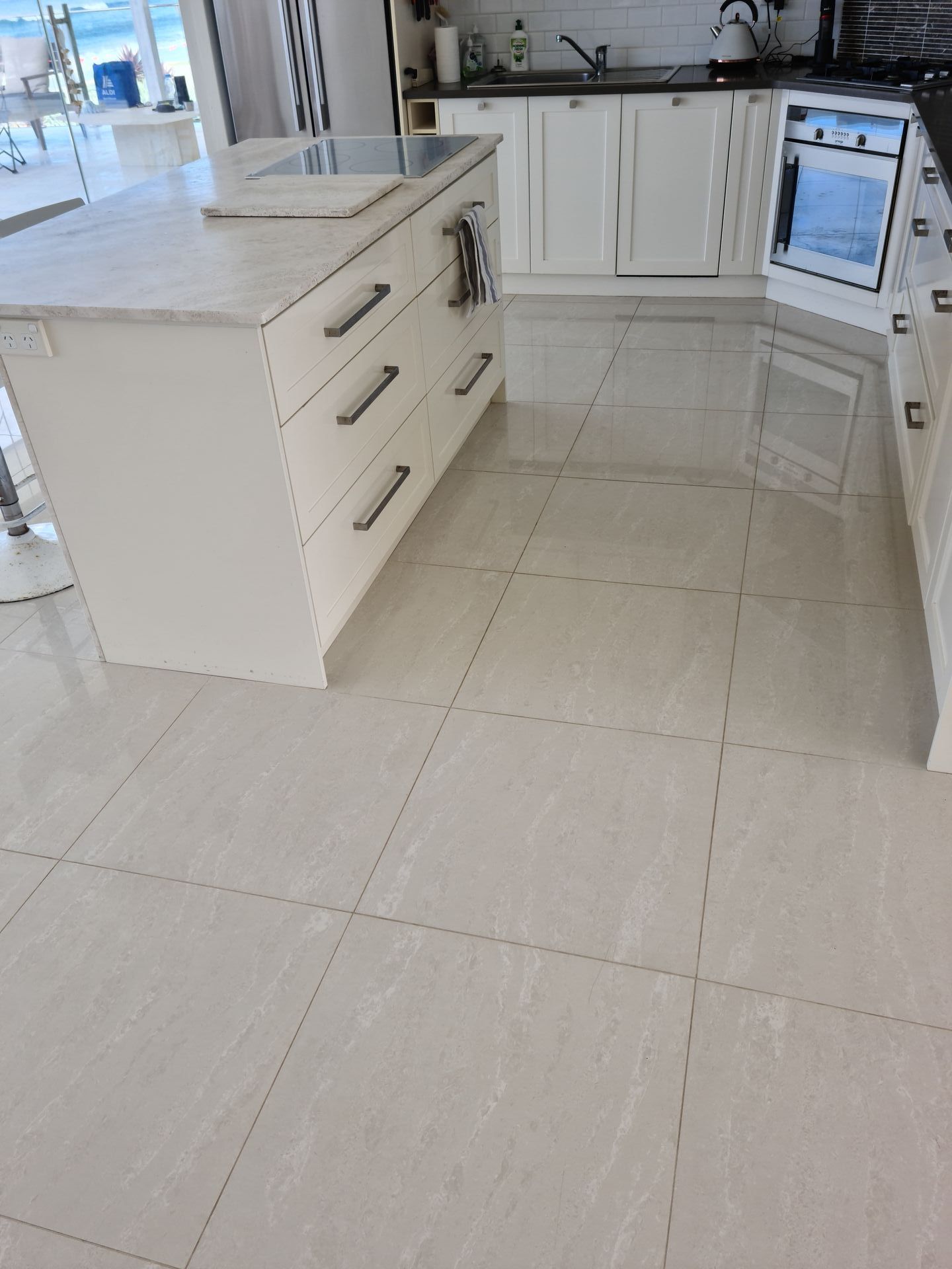 A kitchen with white cabinets and a tiled floor — South Coast Flooring in Berkeley, NSW