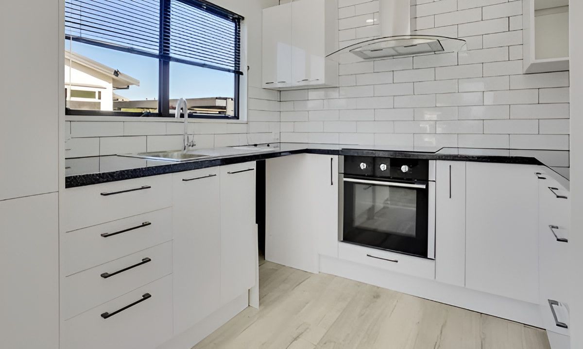 A Kitchen With White Cabinets, Black Appliances and a Window — South Coast Flooring in Shellharbour, NSW