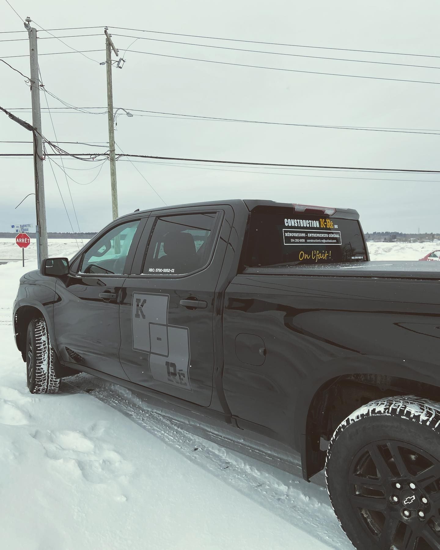 Un camion noir est garé dans la neige avec la lettre k sur le côté
