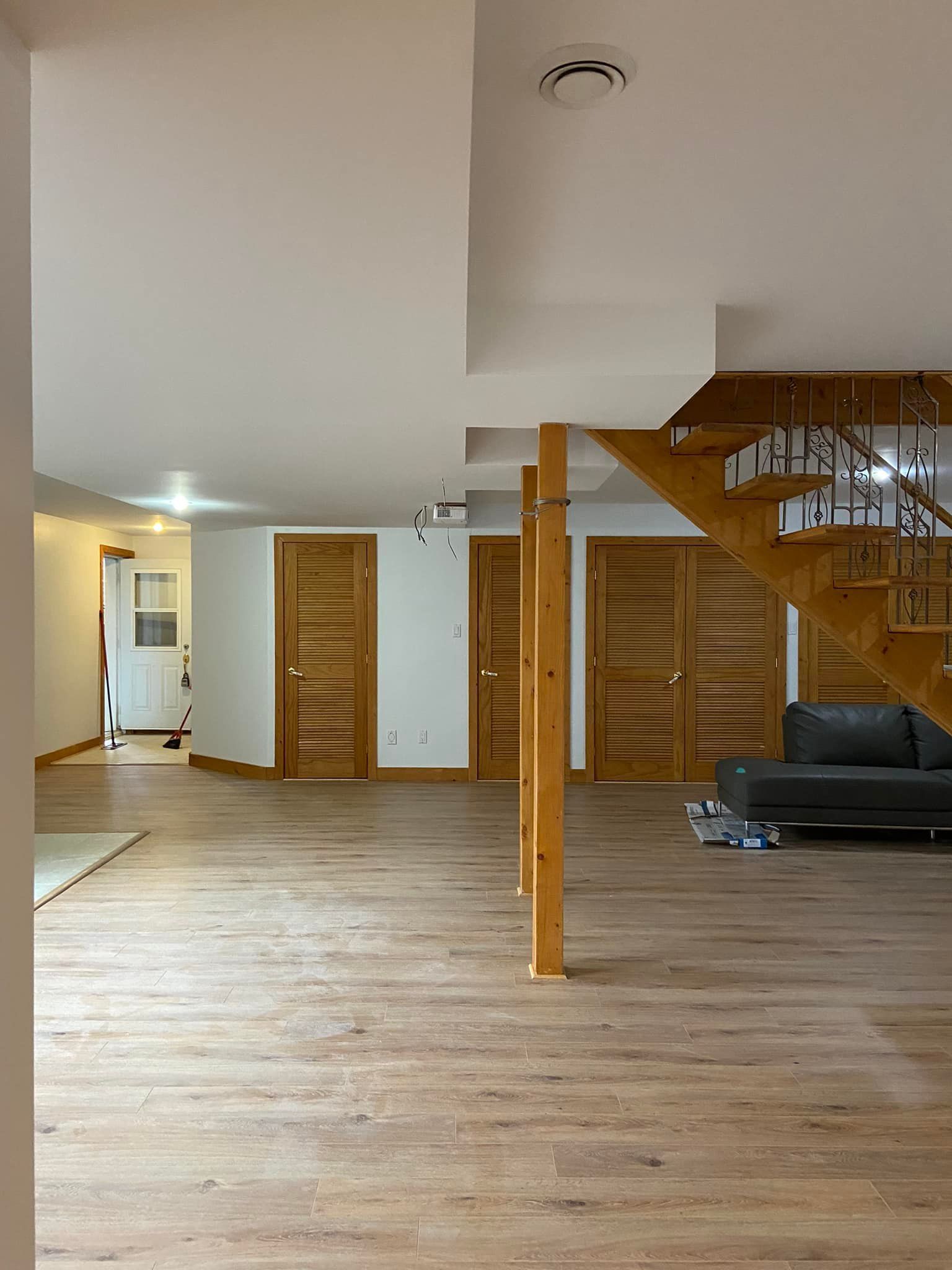 Un salon avec un canapé et des escaliers en arrière-plan.