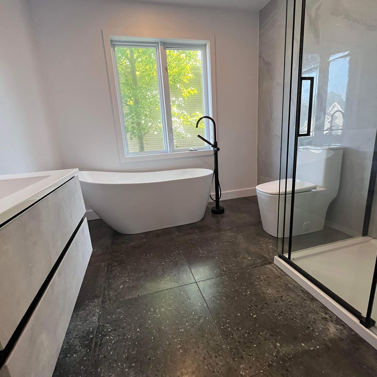 Une salle de bain avec baignoire, WC, douche et fenêtre.