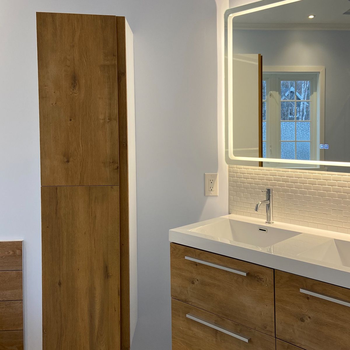 Une salle de bain avec lavabo, miroir et armoires en bois.