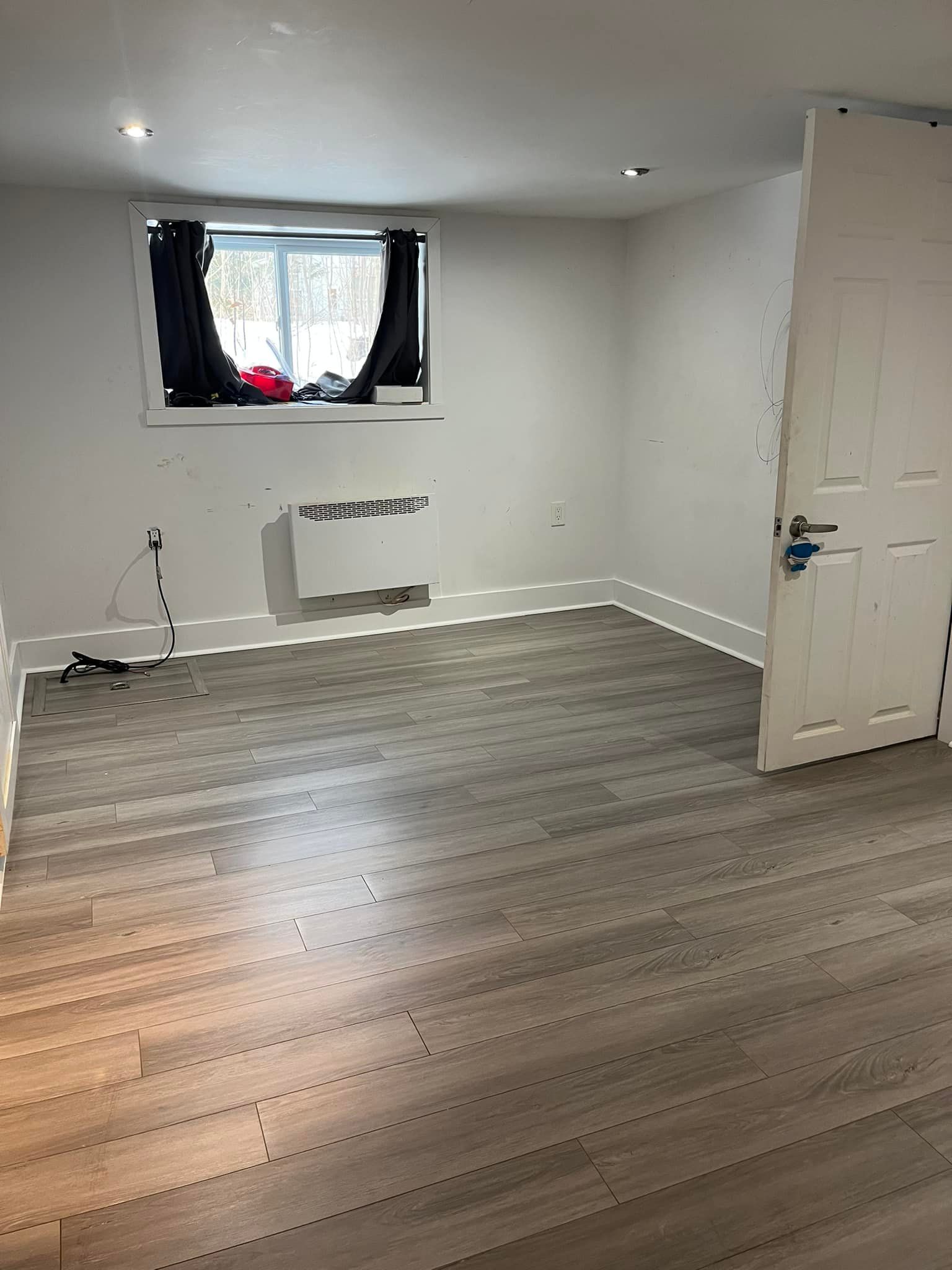 Une pièce vide avec du parquet et une fenêtre.