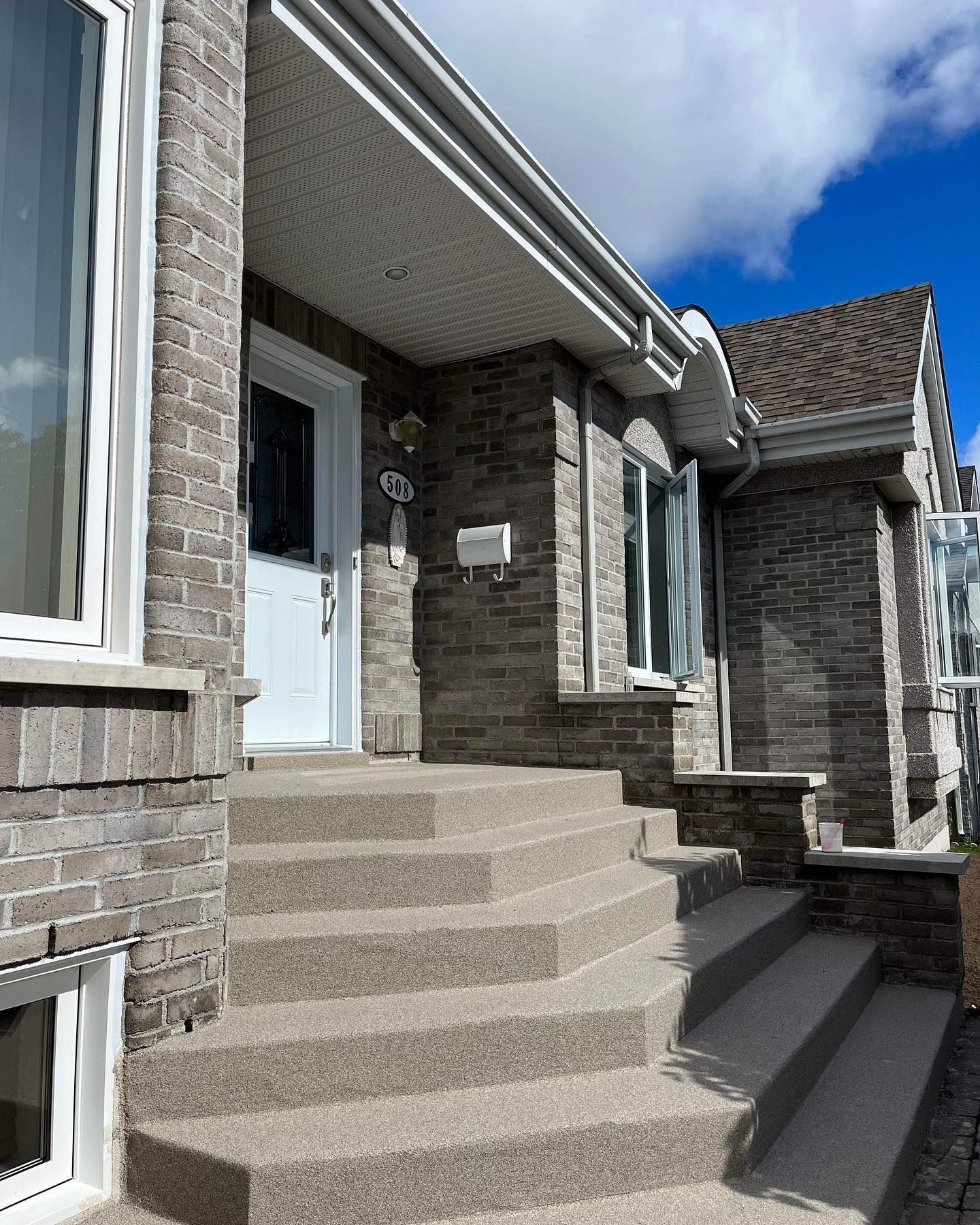 Une maison en briques avec des escaliers menant à la porte d'entrée