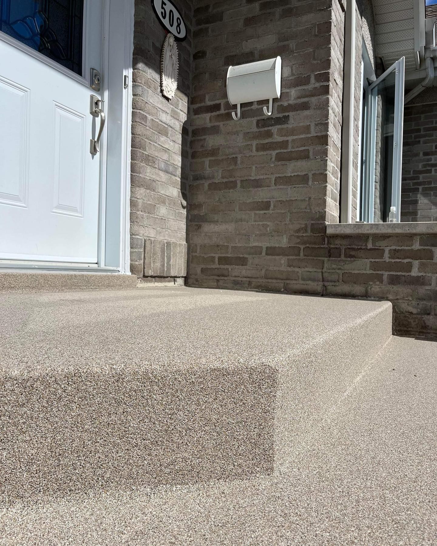 Un bâtiment en briques avec une porte blanche et des escaliers qui y mènent.