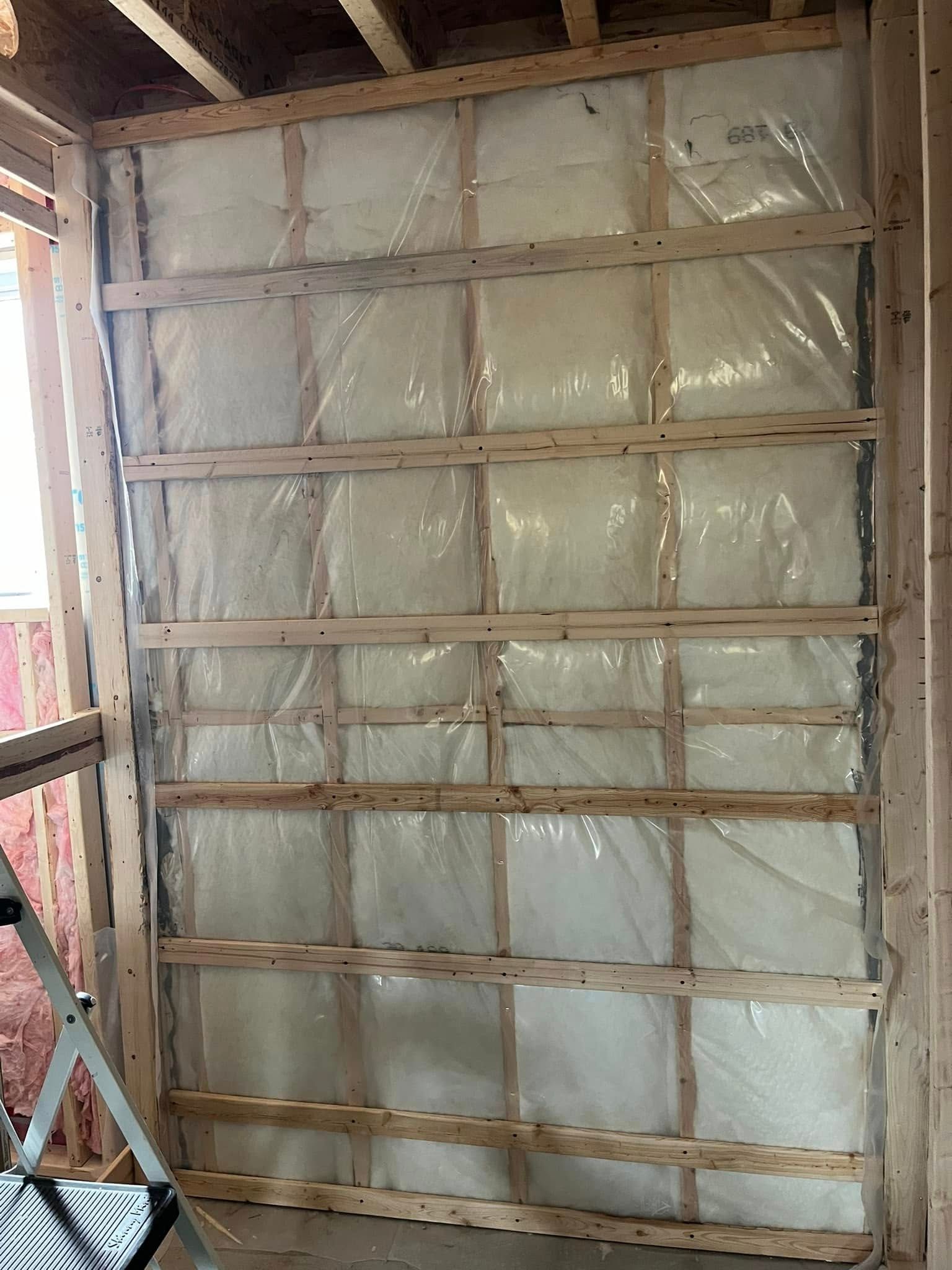 Un mur est isolé avec du plastique et du bois.