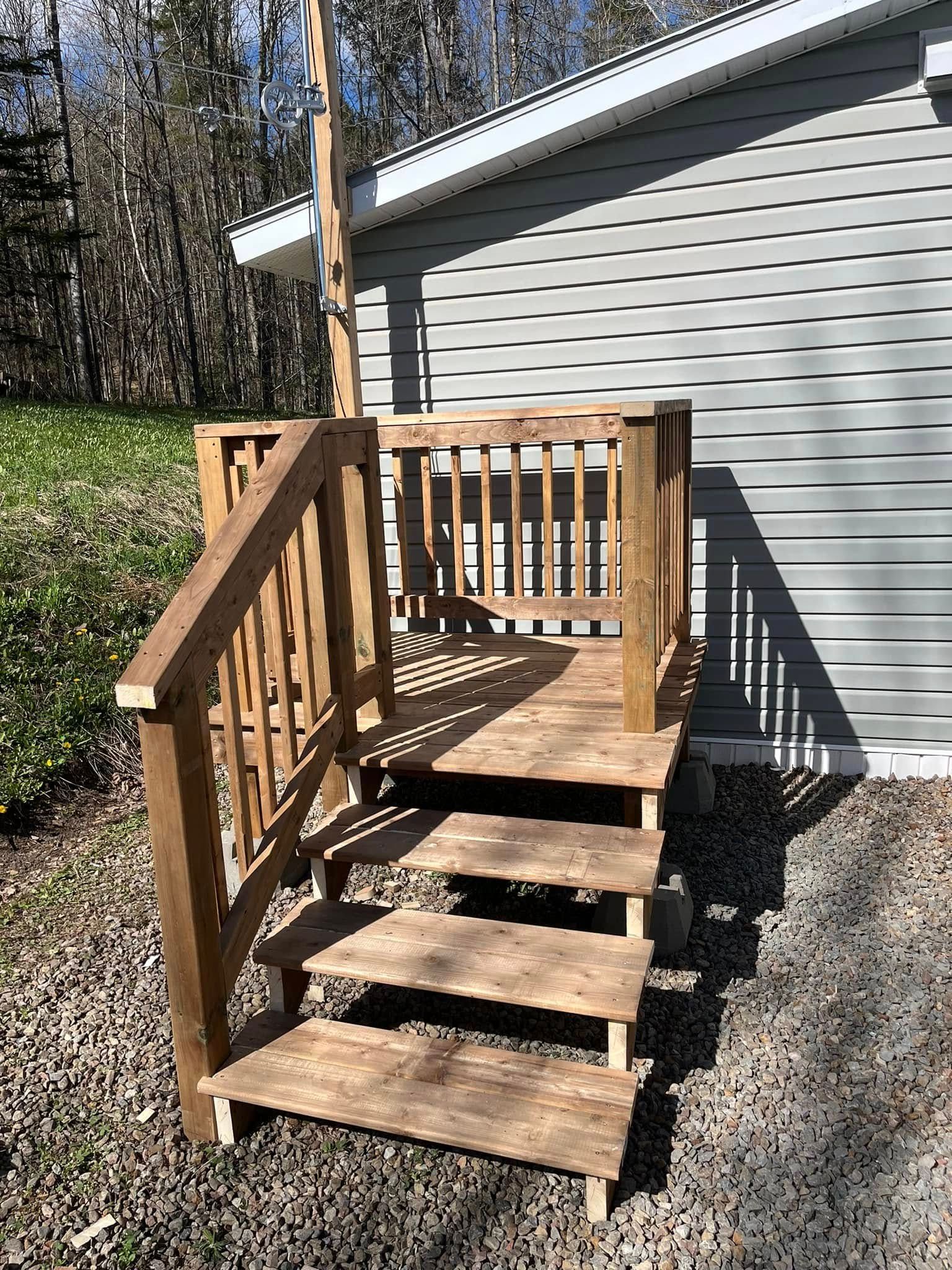 Une terrasse en bois avec des escaliers qui y mènent se trouve devant une maison.