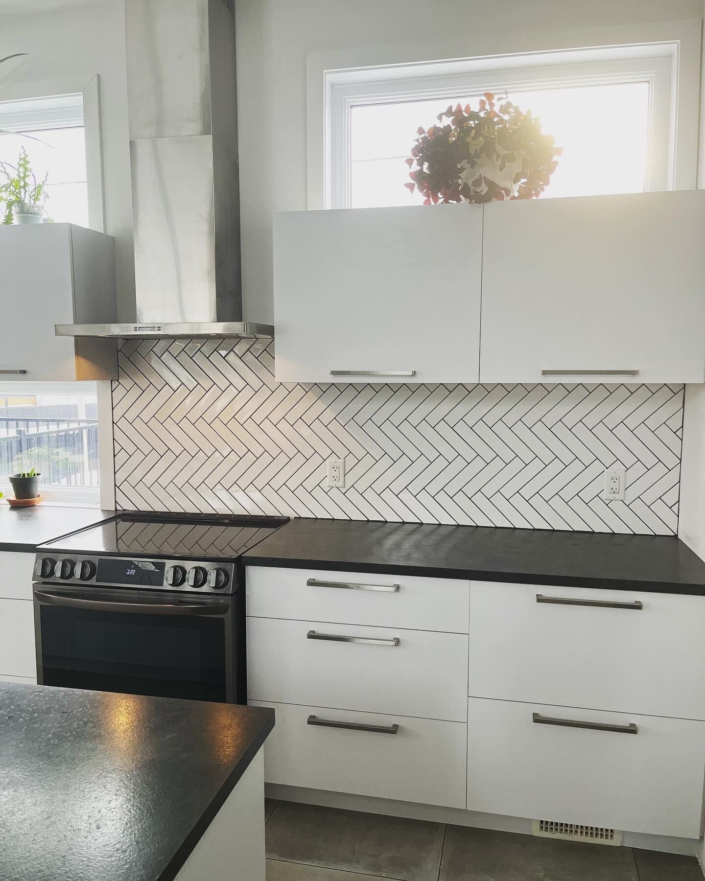 Une cuisine avec des armoires blanches et des comptoirs noirs