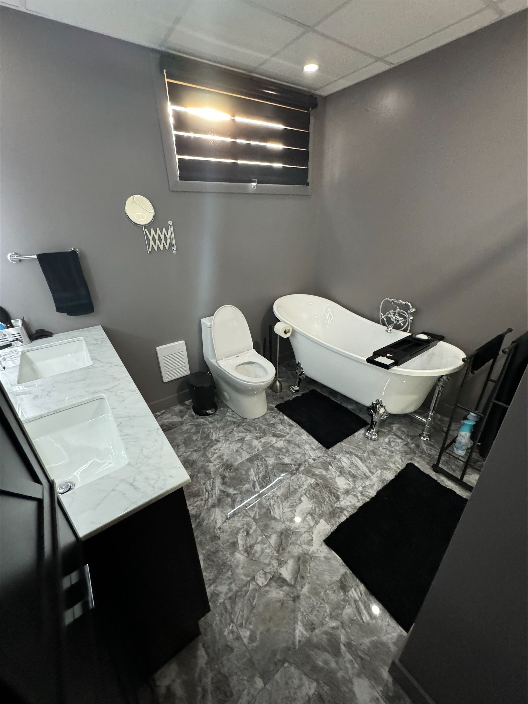 Une salle de bain avec baignoire, WC, lavabo et miroir.