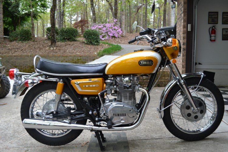 Right full view of the 1971 Yamaha XS1B with trees and flowers in the background