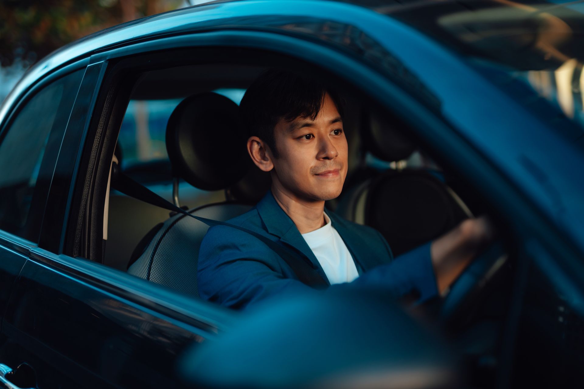 Driver in blue jacket inside car with blurred window view. Driver in blue jacket inside car with blurred window view.