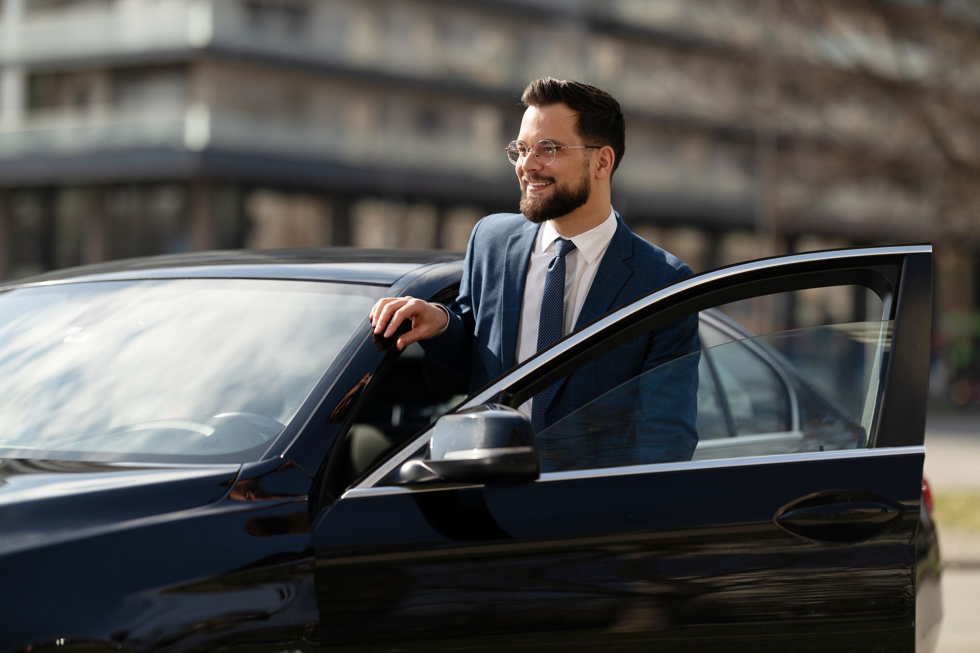 Person in suit stands beside open car door, ready to enter. Person in suit stands beside open car door, ready to enter.
