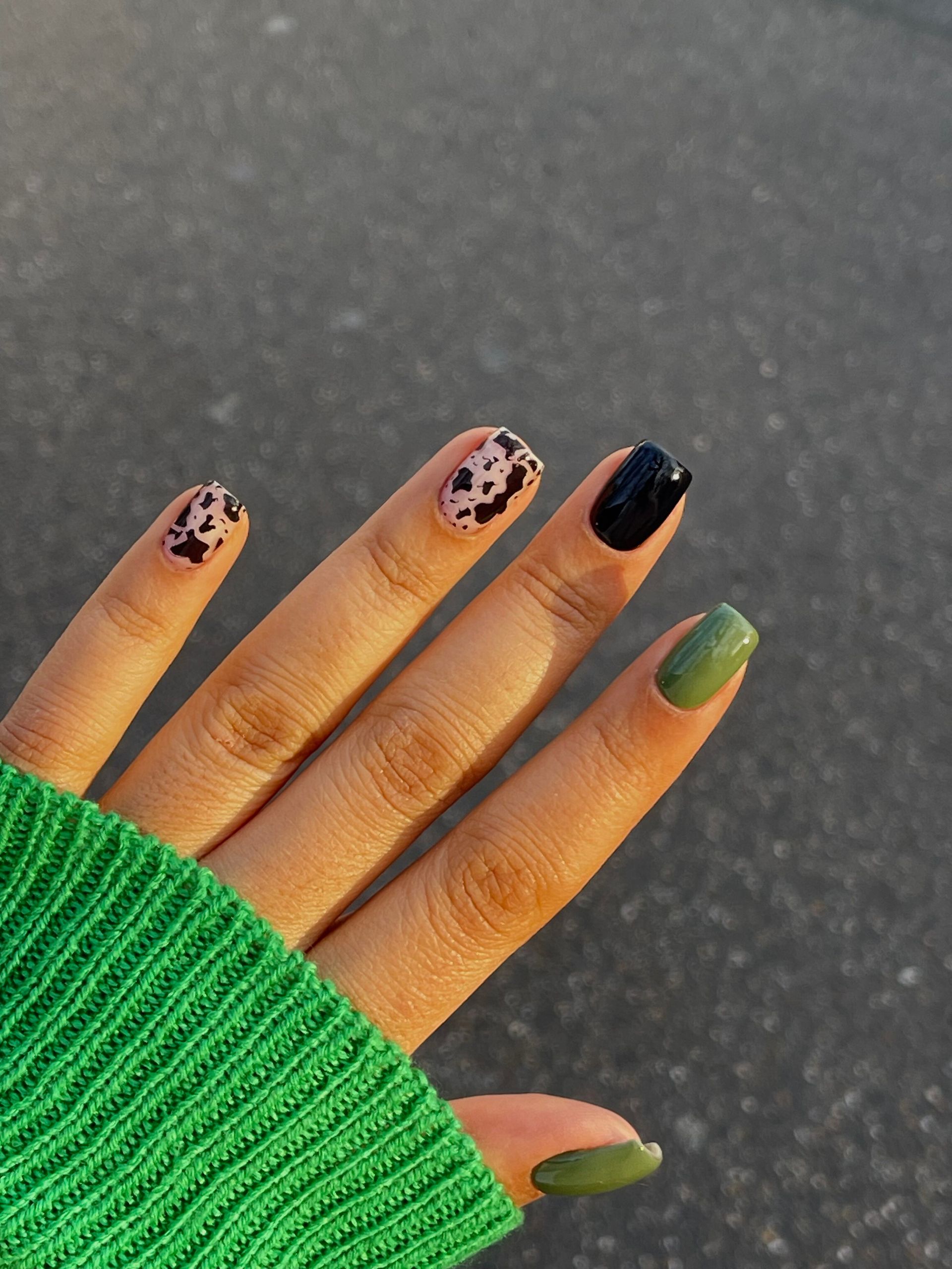 Eine Nahaufnahme der Nägel einer Person mit einem grünen Pullover auf