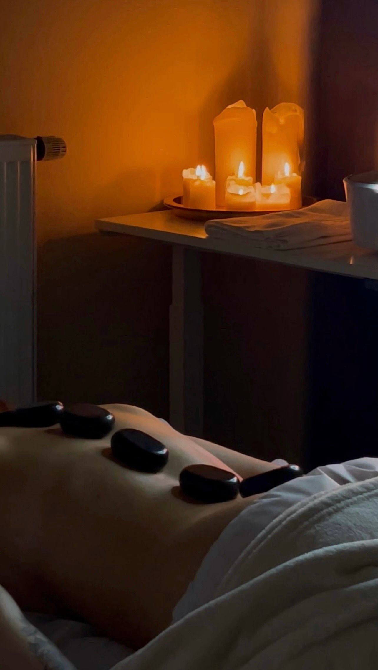 Eine Person bekommt eine Massage mit heißen Steinen auf dem Rücken.