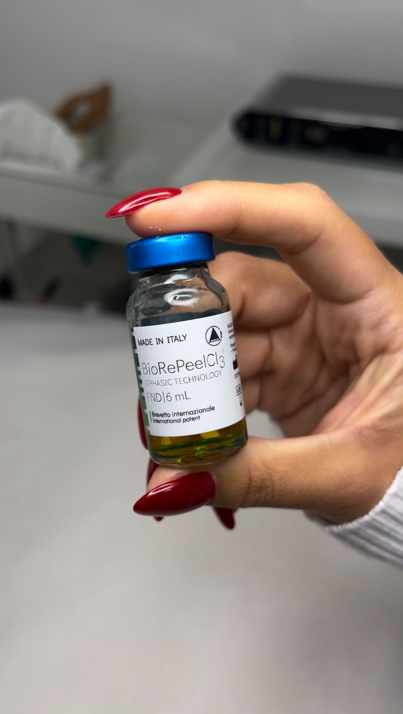 Eine Frau hält eine kleine Flasche mit Flüssigkeit in der Hand.