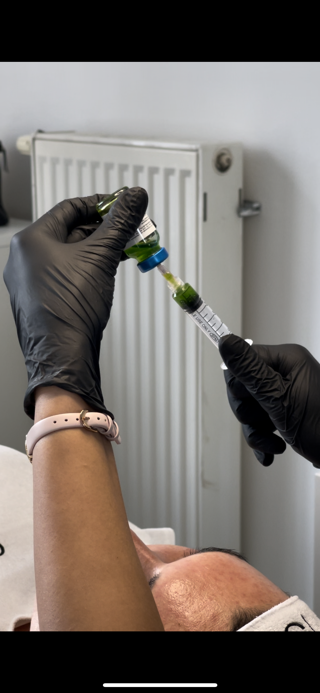 Eine Person mit schwarzen Handschuhen hält eine Spritze in der Hand.