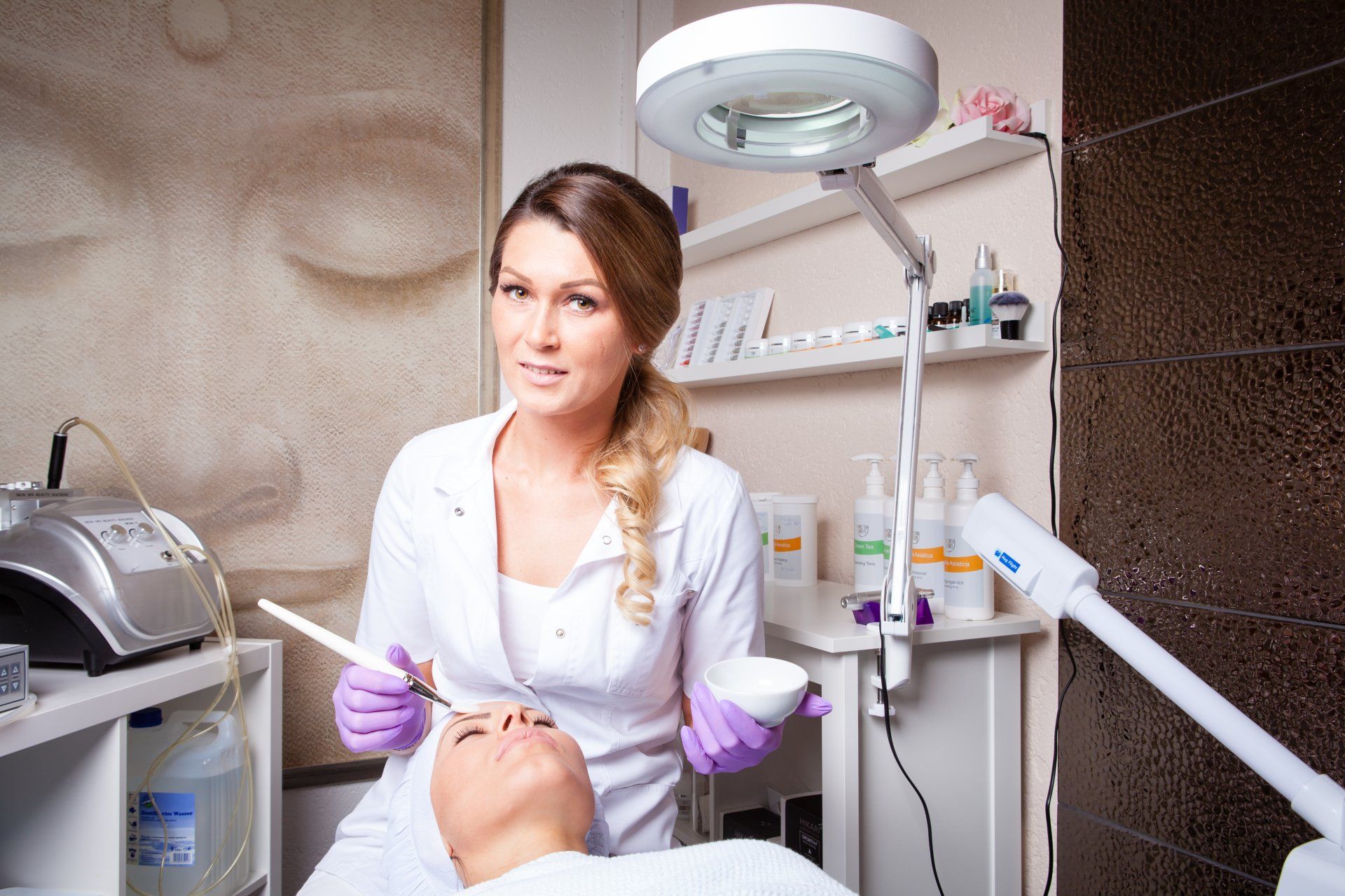 In einem Schönheitssalon trägt eine Frau eine Maske auf das Gesicht eines Mannes auf.