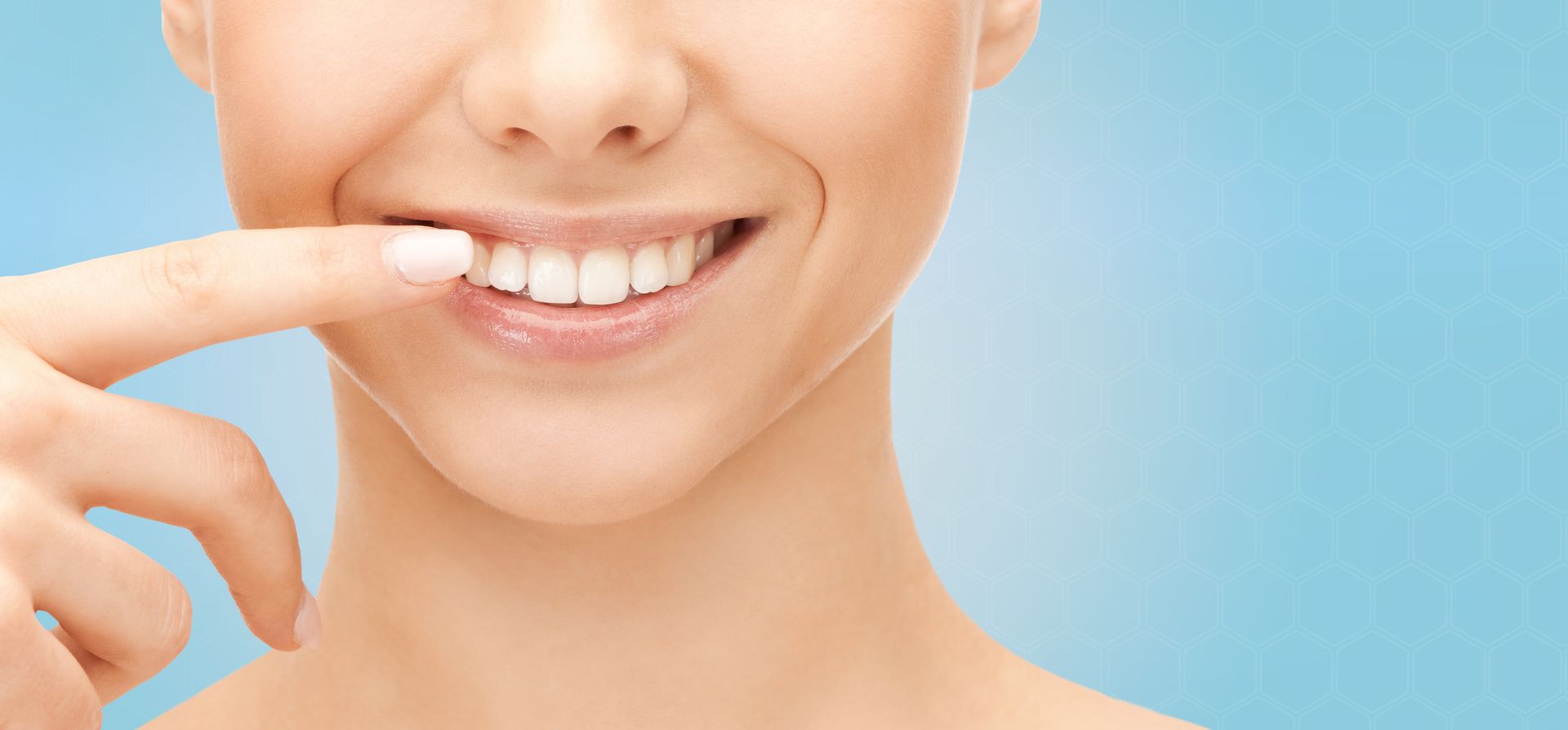 Femme souriante, pointant ses dents du doigt. Fond bleu.Hollywoodsmile