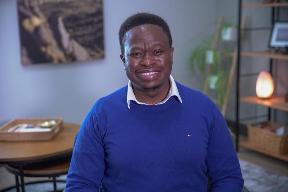 A woman with curly hair is smiling and wearing a white shirt.
