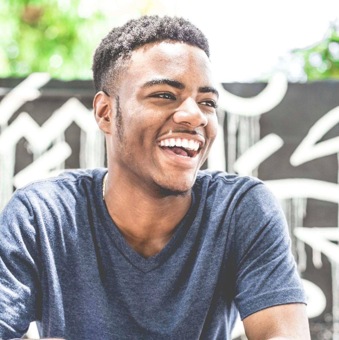 Confident young man sitting outside and smiling. Confident young man sitting outside and smiling.