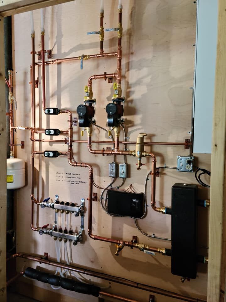 Copper pipes and mechanical components for a heating system mounted on a wooden board.