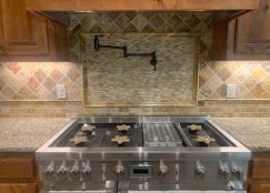 Stainless steel stove with back splash, pot filler, and decorative tile.