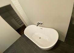 White oval bathtub in a modern bathroom, with dark faucet and gray tile flooring.