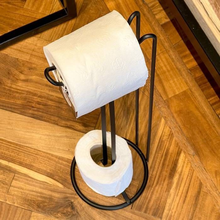 Un rollo de papel higiénico está sobre un soporte de papel higiénico negro.