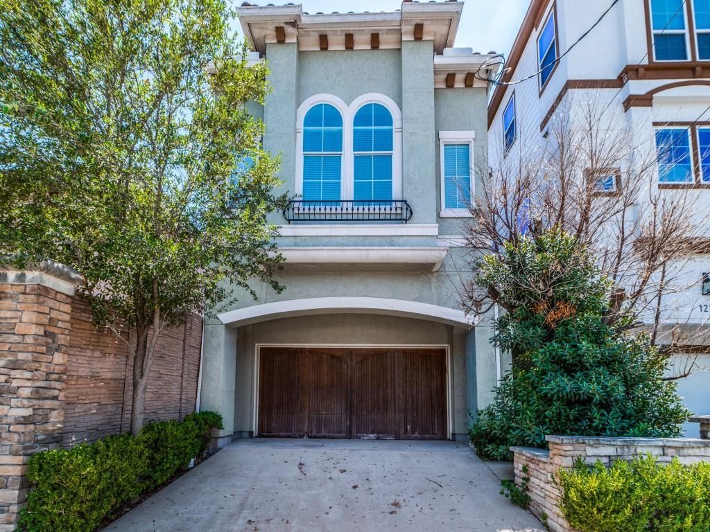Two-story home with light blue facade, arched garage door, and double arched windows.
