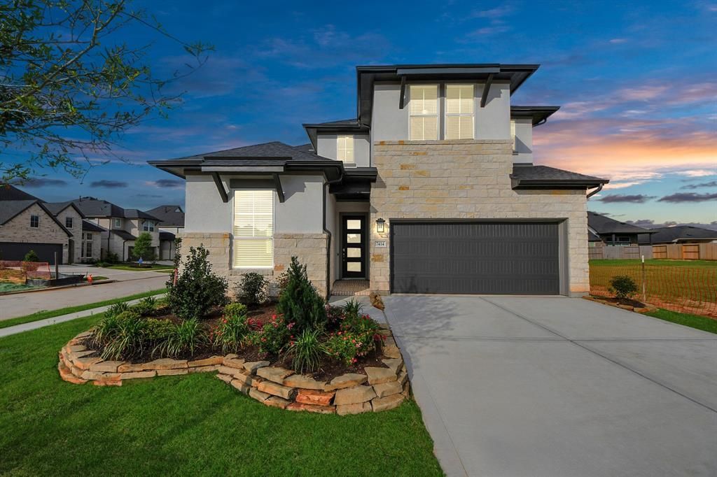Modern two-story house with gray stucco, stone accents, and a landscaped front yard.