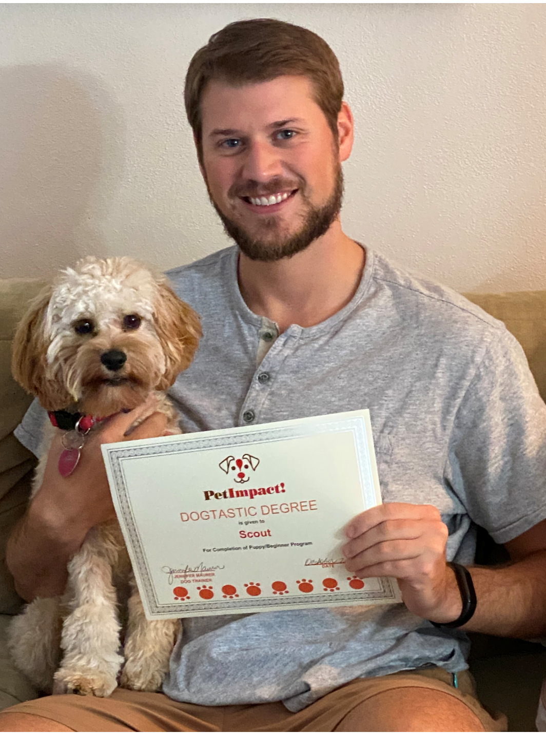 Man smiling, holding a small dog and certificate that says 