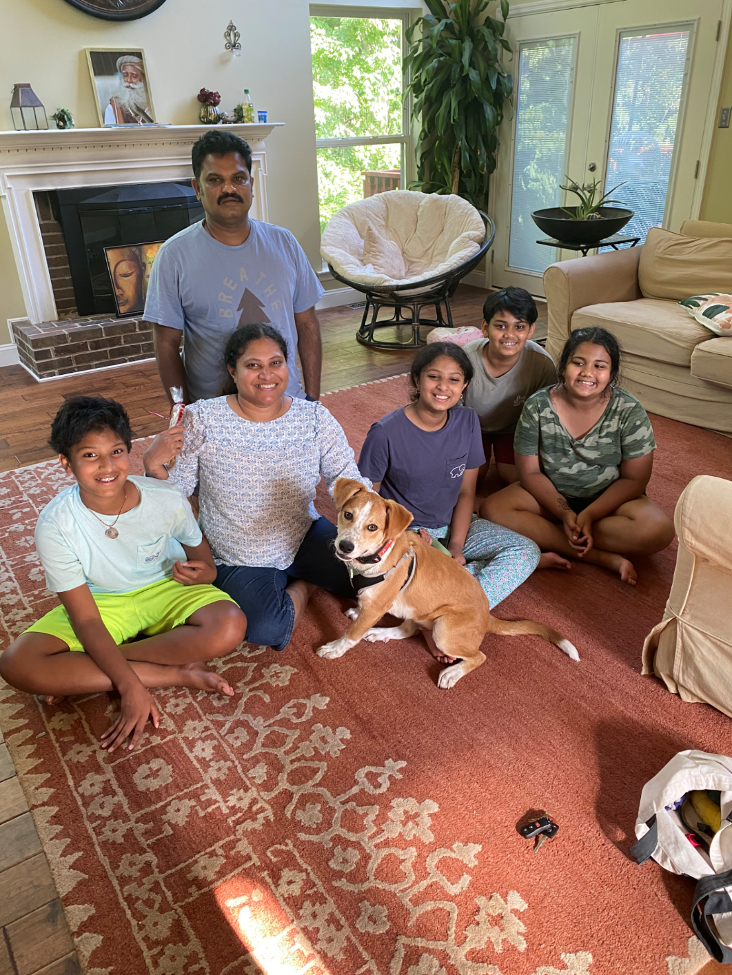 Family and dog pose on a rug in a living room, smiling at the camera.