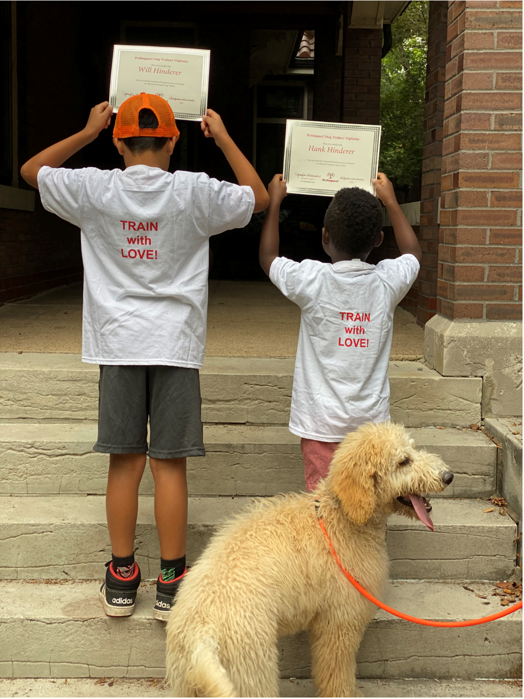Two boys hold certificates, wearing 