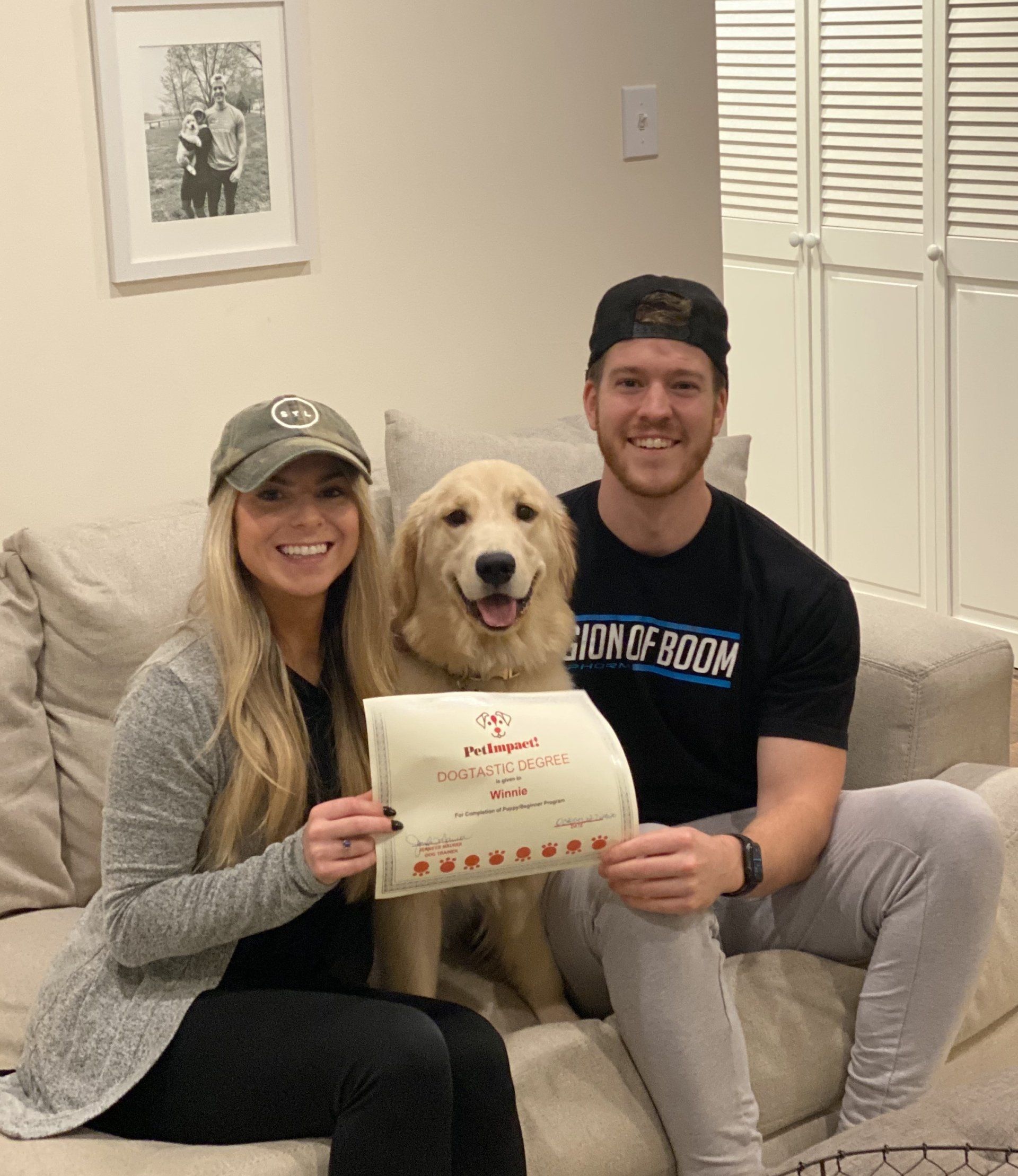 Couple with golden retriever holding certificate; posing on couch.