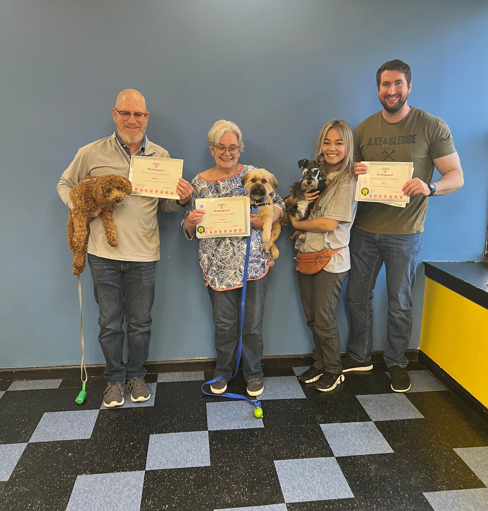 A group of people standing next to each other holding dogs and certificates
