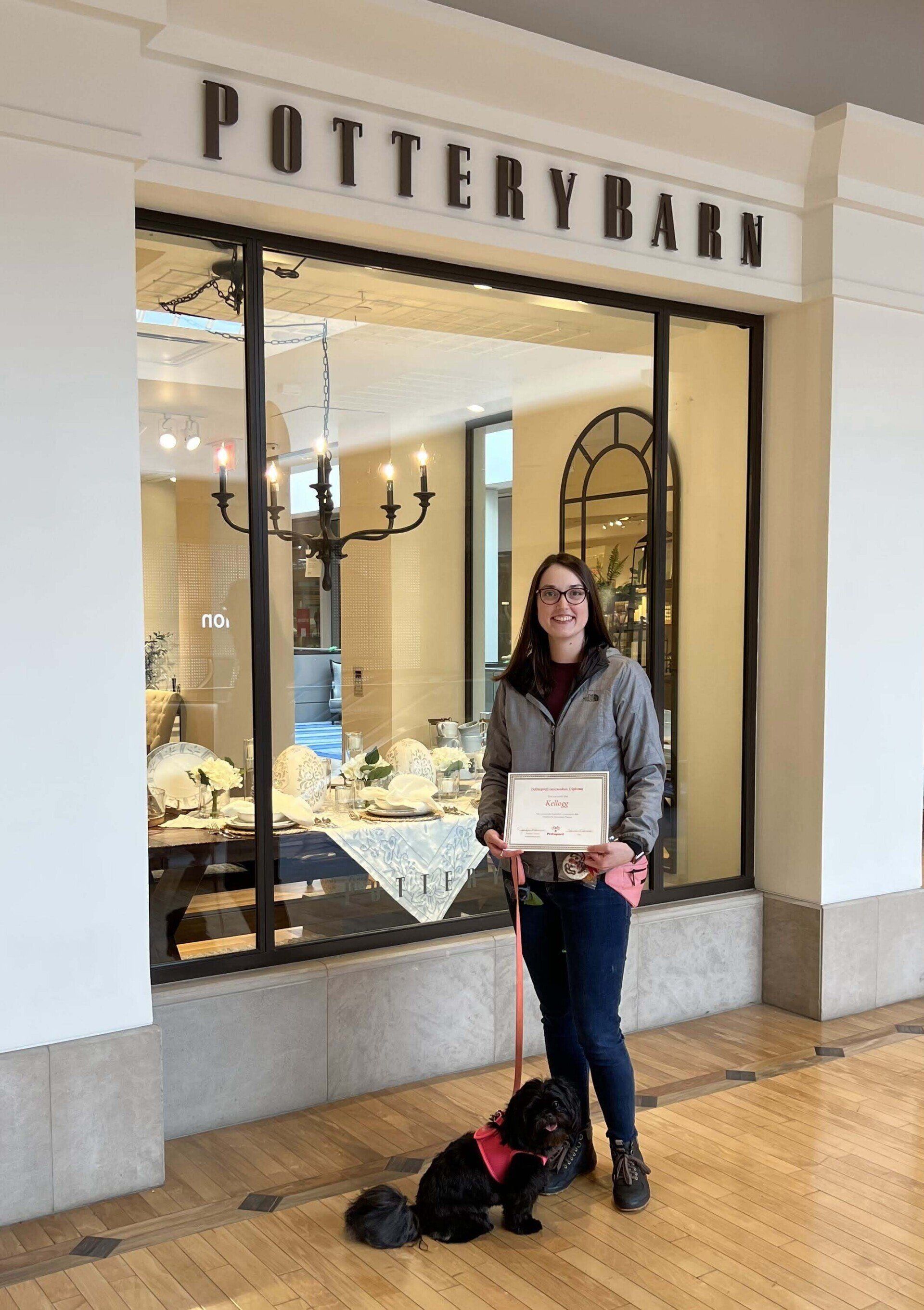 Woman with dog outside Pottery Barn holding a certificate.