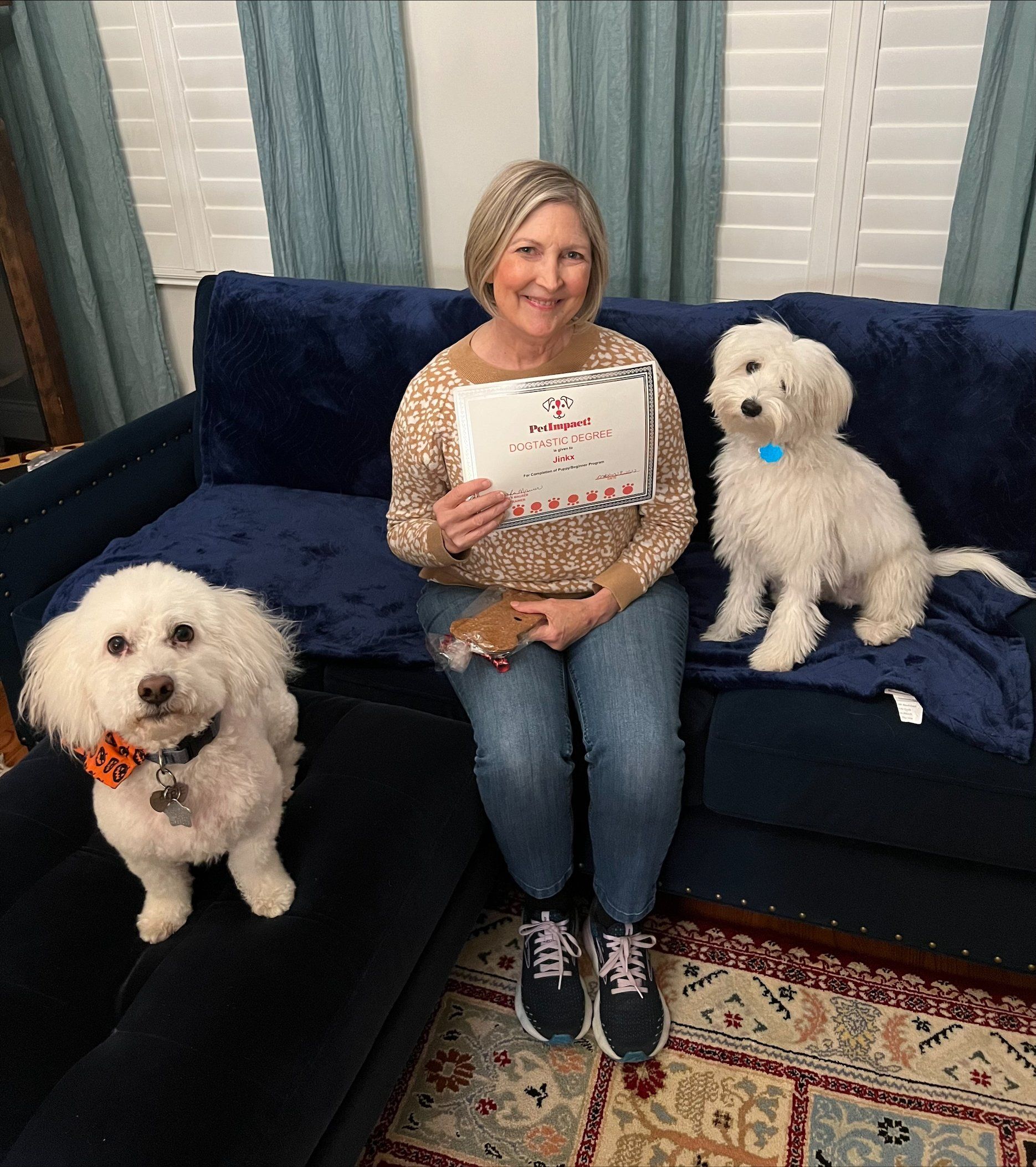 Woman on blue couch with two white dogs; holding card.