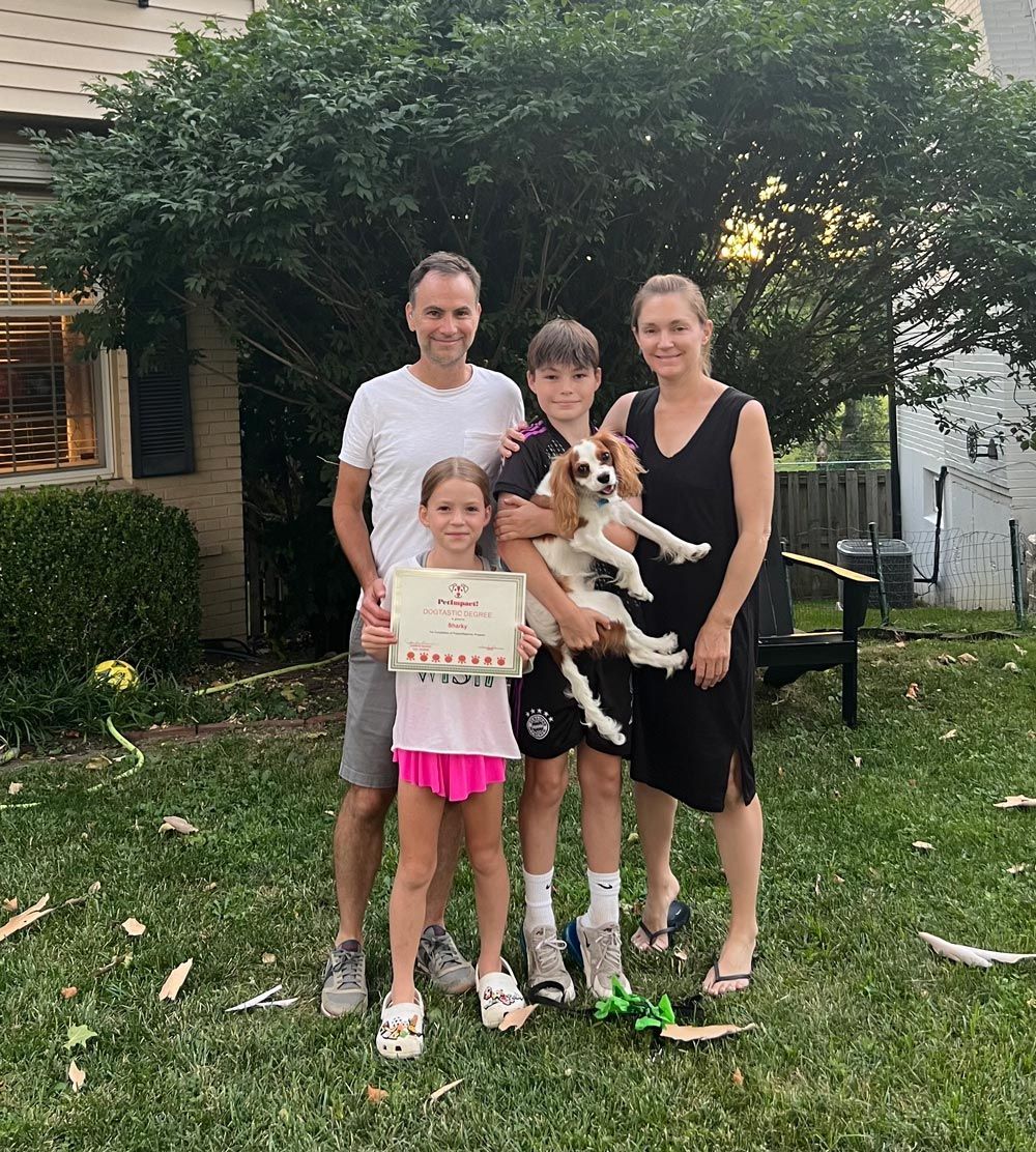 A family posing for a picture with a dog and a certificate