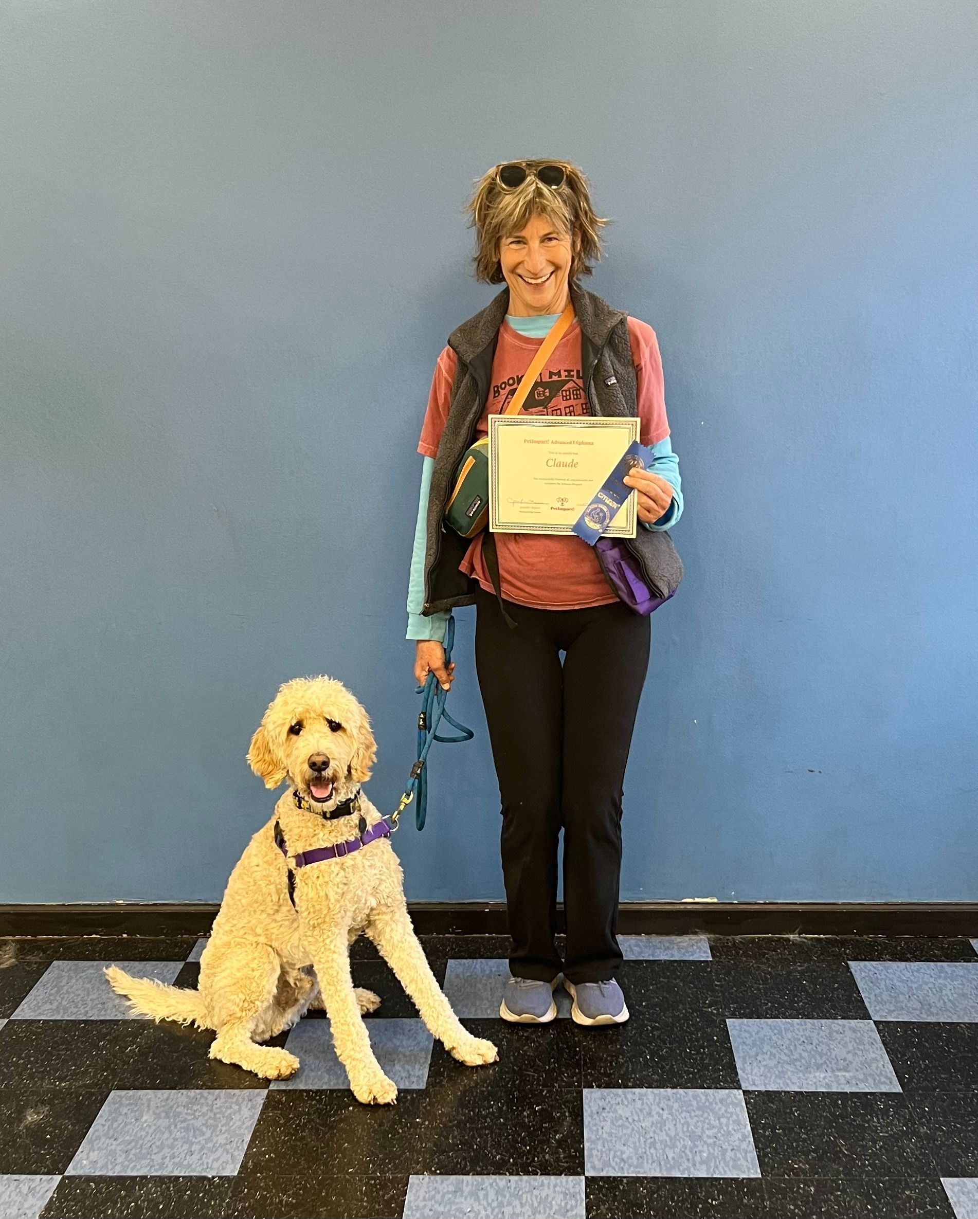 Woman and goldendoodle dog pose after a dog training class, both looking at the camera.