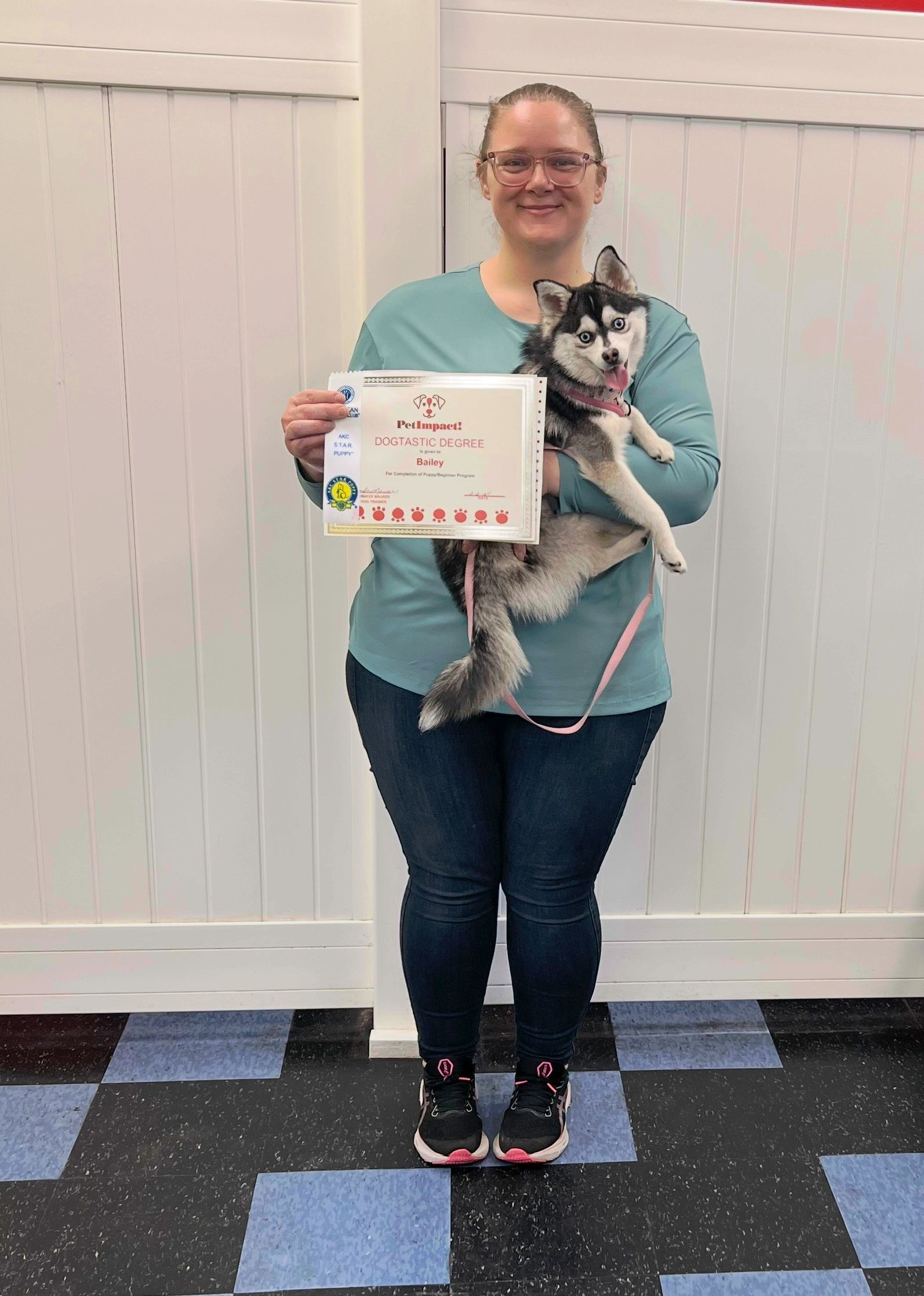 A woman is holding a husky dog and holding a certificate.