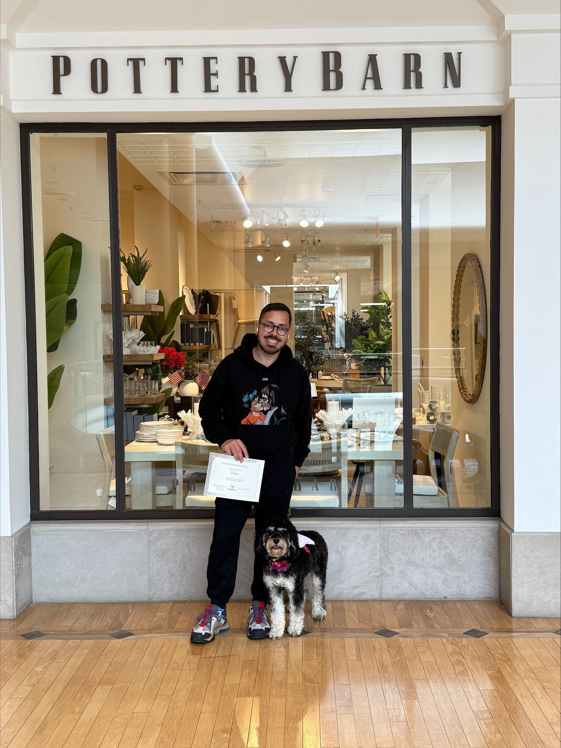 A man and a dog are standing in front of a pottery barn store