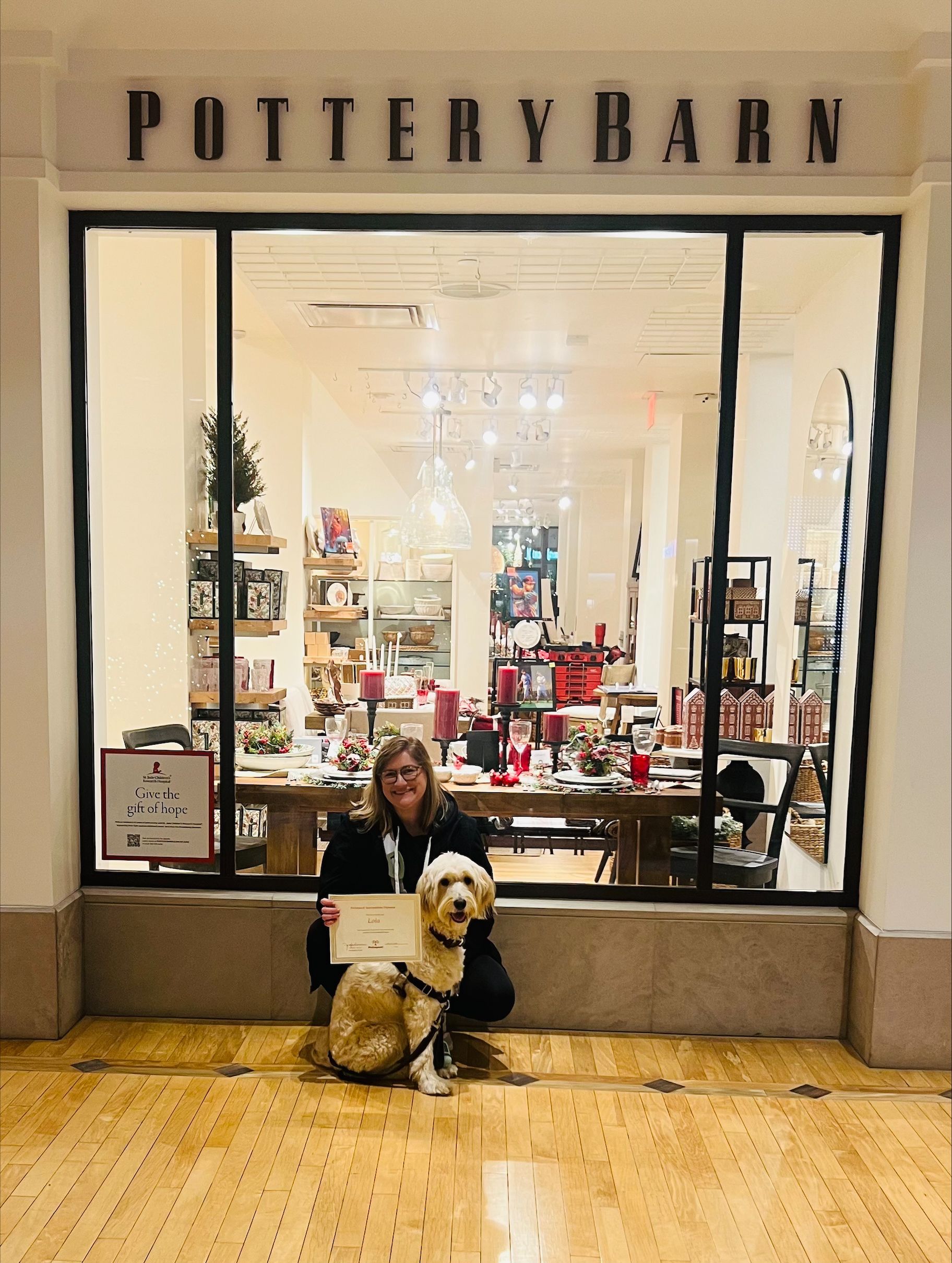 A woman and a dog are standing in front of a pottery barn store.