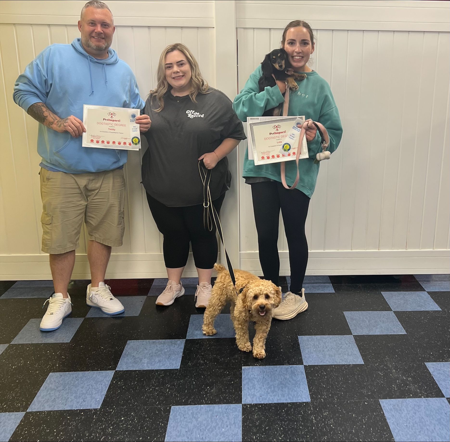A man and two women standing next to a dog holding certificates