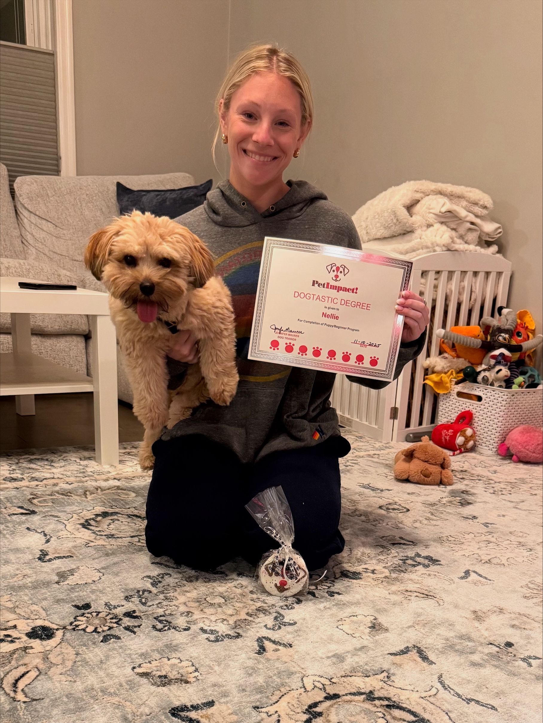 Woman kneeling, holding dog and sign, with ornament on rug.